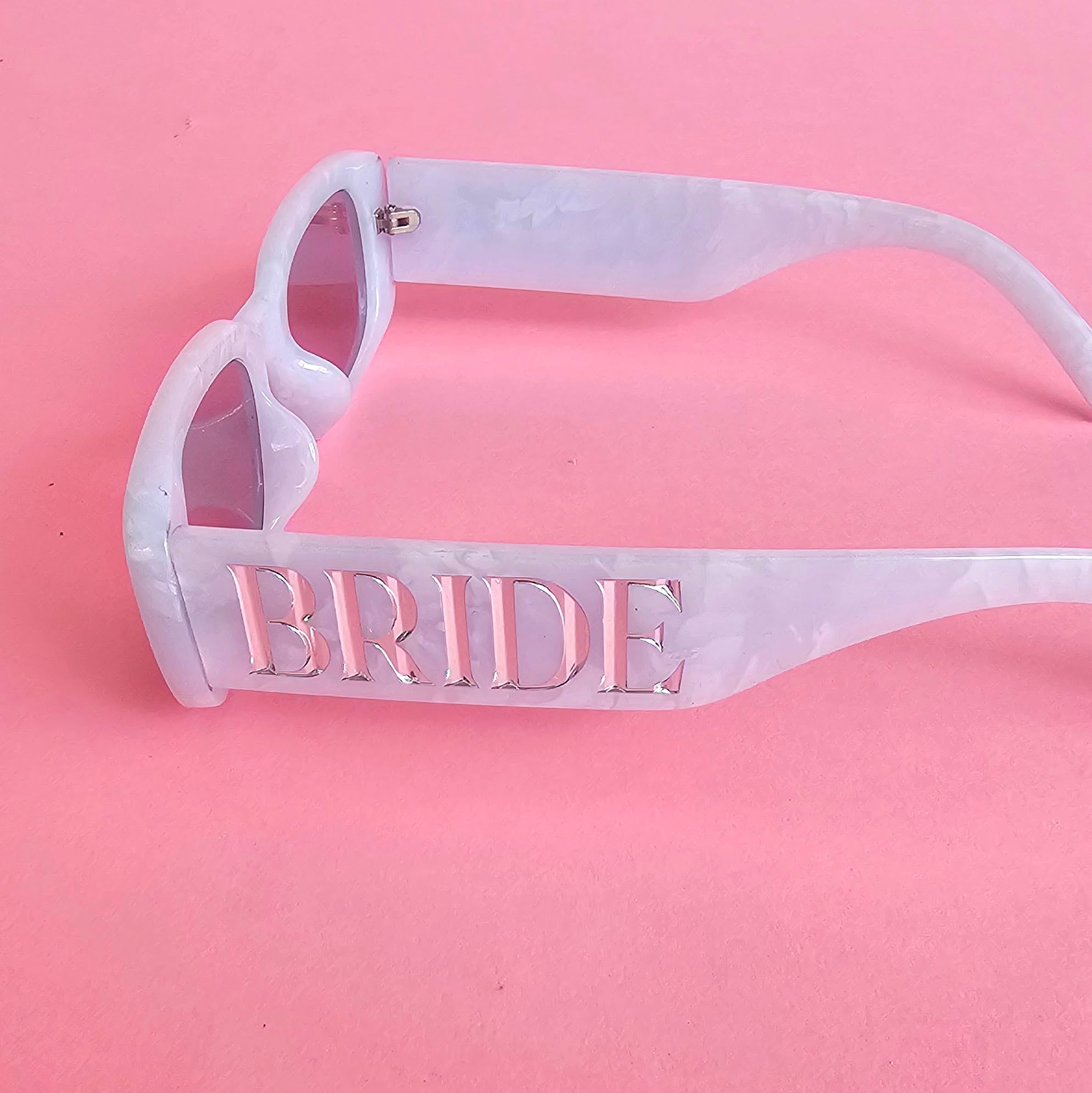 Pearl white bride sunglasses with silver BRIDE lettering and light grey lenses