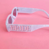 Pearl white bride sunglasses with silver BRIDE lettering and light grey lenses