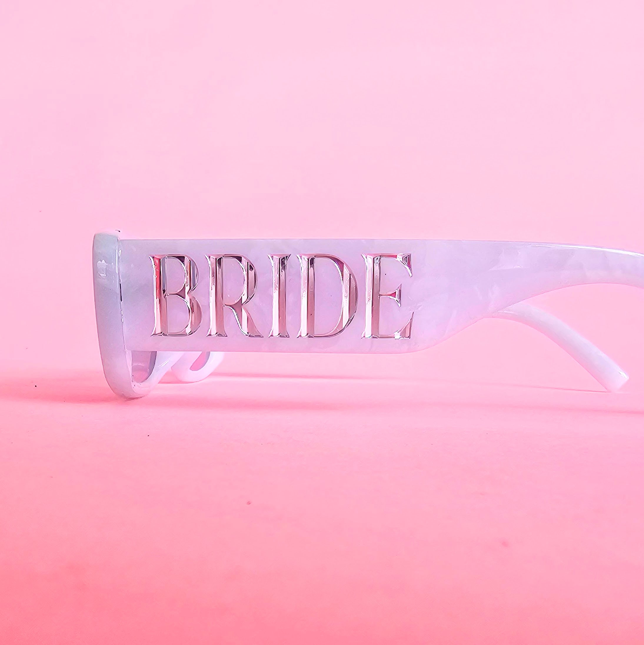 Pearl white bride sunglasses with silver BRIDE lettering and light grey lenses
