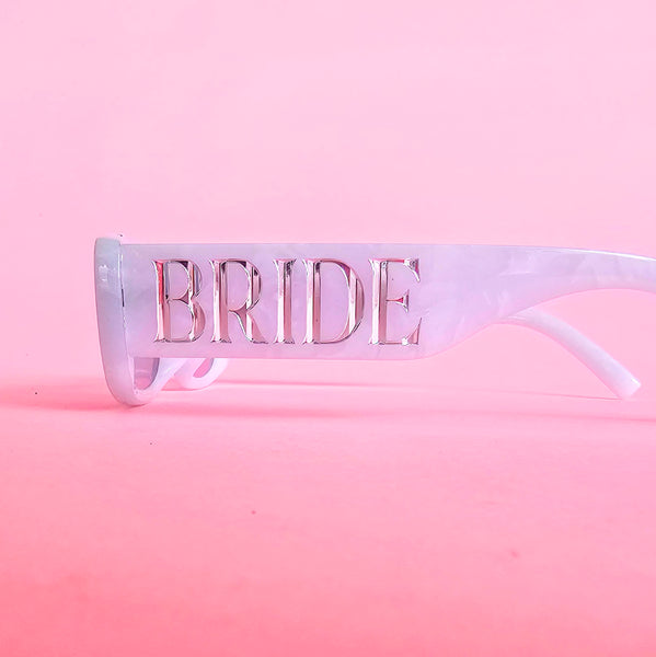 Pearl white bride sunglasses with silver BRIDE lettering and light grey lenses