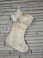 Ivory holiday stocking with cozy faux fur top, pom balls, and custom gold HTV vinyl name applied by hand