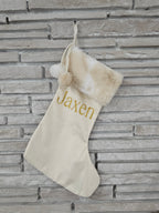 Handmade ivory stocking with neutral faux fur trim, pom balls, and personalized gold HTV vinyl name