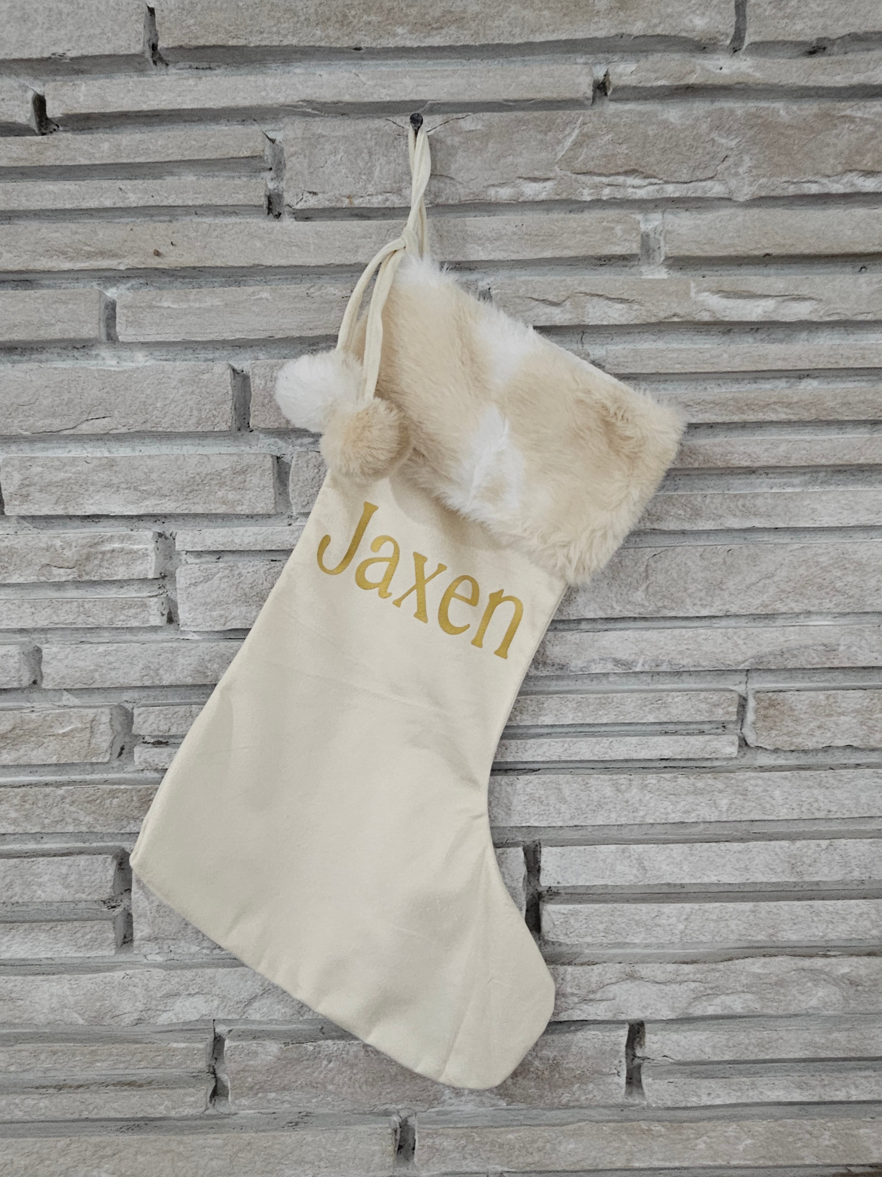 Handmade ivory stocking with neutral faux fur trim, pom balls, and personalized gold HTV vinyl name
