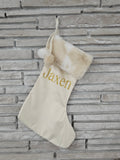 Handmade ivory stocking with neutral faux fur trim, pom balls, and personalized gold HTV vinyl name