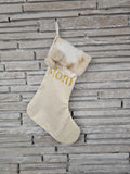 Premium ivory Christmas stocking with gold HTV vinyl name, faux fur cuff, and pom ball accents, handmade in Ohio