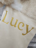 Close-up of ivory personalized Christmas stocking featuring plush neutral faux fur trim and gold HTV vinyl name detail