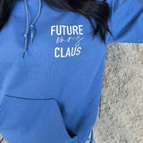 Person wearing a blue hoodie with 'FUTURE CLAUS' text, lying on a stone surface.