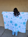 Person holding a white blanket with blue snowflake patterns.