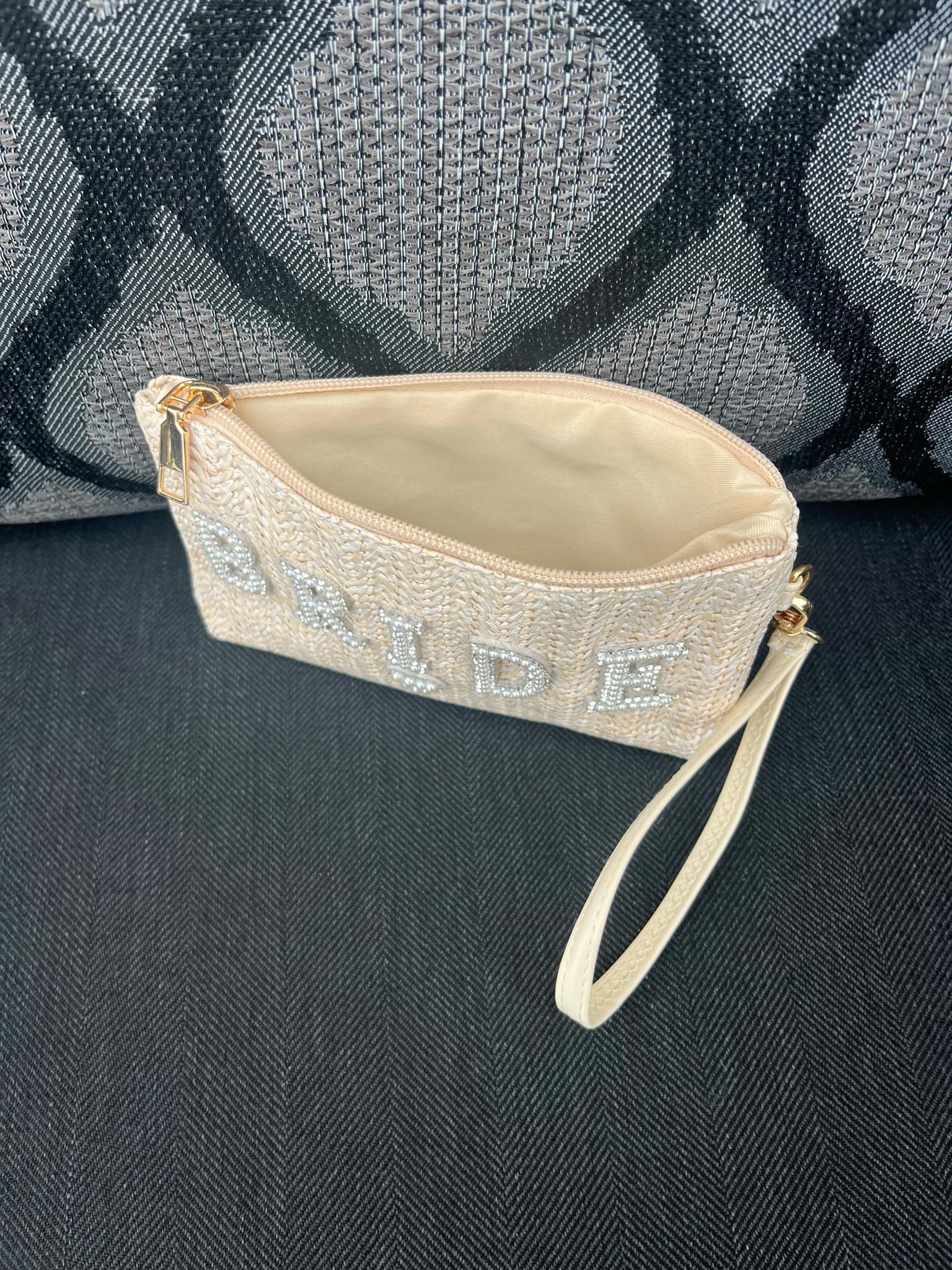 Beige clutch bag with 'BRIDE' text on a dark textured surface