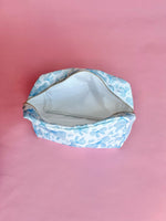 White makeup bag with an all-over light blue bow pattern, featuring a rectangular shape and zippered closure — perfect for brides and travel use.