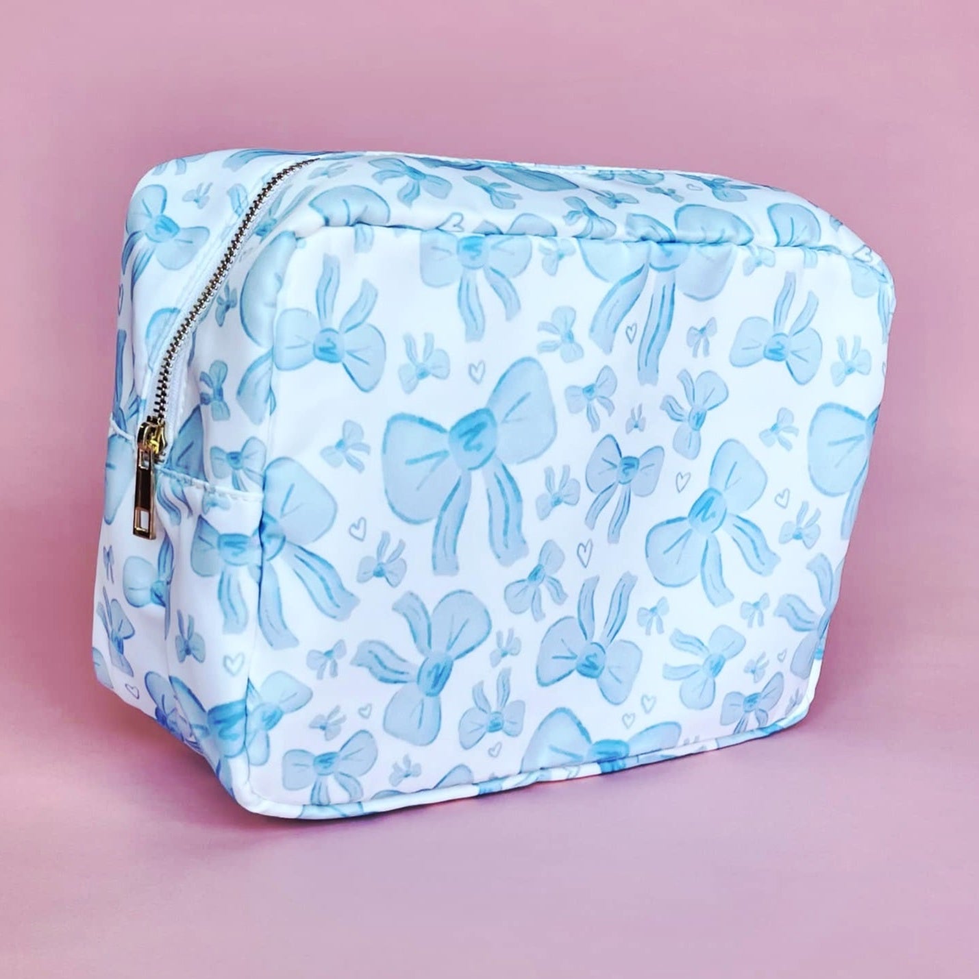 White makeup bag with an all-over light blue bow pattern, featuring a rectangular shape and zippered closure — perfect for brides and travel use.