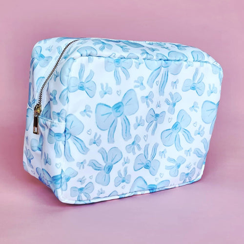 White makeup bag with an all-over light blue bow pattern, featuring a rectangular shape and zippered closure — perfect for brides and travel use.