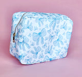 White makeup bag with an all-over light blue bow pattern, featuring a rectangular shape and zippered closure — perfect for brides and travel use.