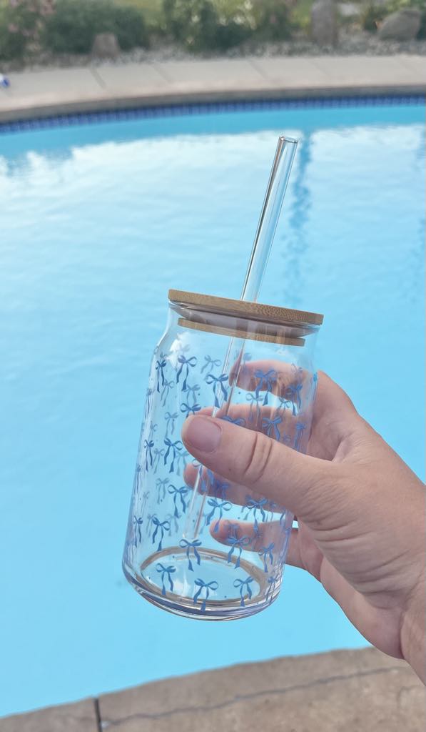 Clear 16oz glass cup with bamboo lid and straw featuring a blue bow pattern, perfect for iced coffee and bridal gifts.