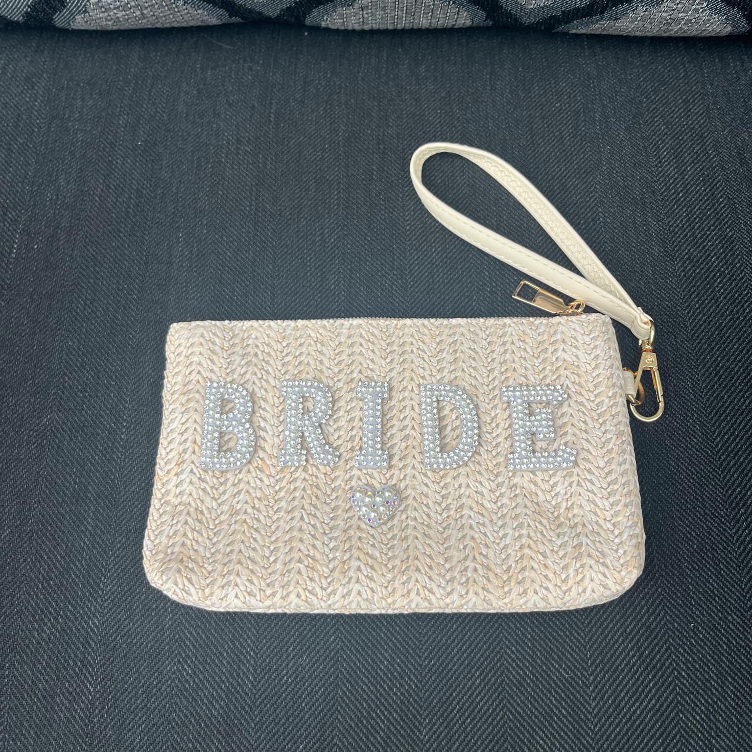 Beige clutch bag with 'BRIDE' text on a dark textured surface