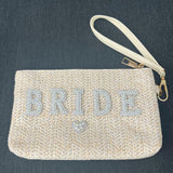 Beige clutch bag with 'BRIDE' in rhinestones on a dark background