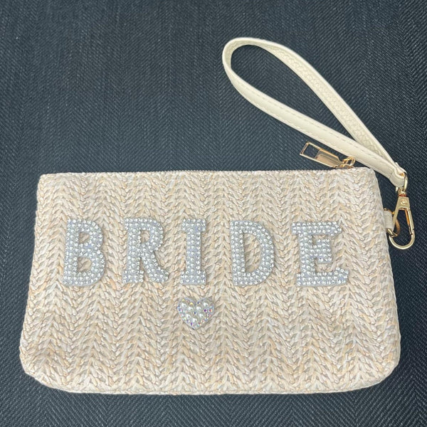 Beige clutch bag with 'BRIDE' in rhinestones on a dark background