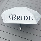 White umbrella with 'BRIDE' text on a wooden surface
