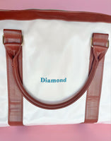 White and brown foldable weekender travel bag with leather-style straps, perfect for brides on the go.