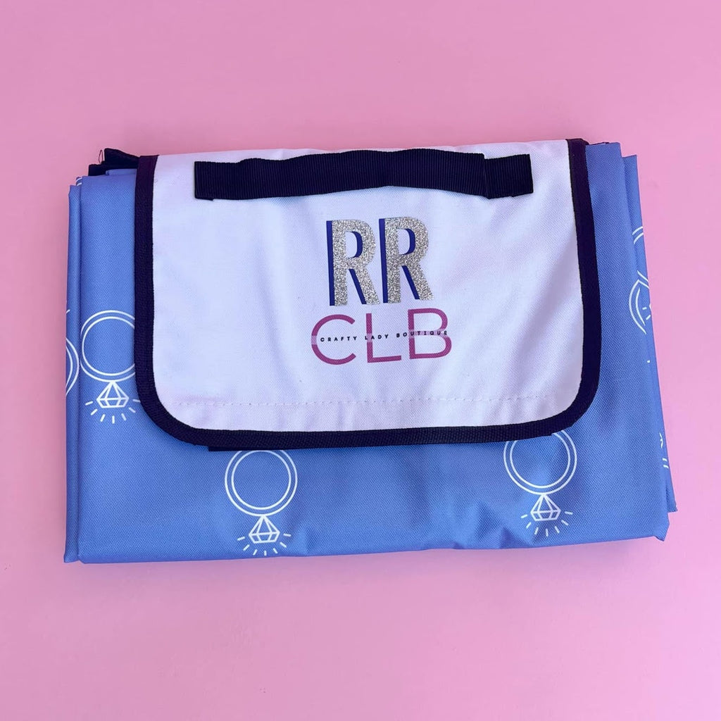 Foldable picnic mat with blue engagement ring print, white inner lining, and personalized flap—perfect for brides, wives, or bridal party outings.