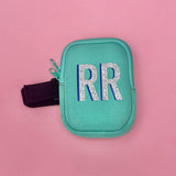Mint green tumbler pouch with glitter monogram, securely wrapped around a textured blue tumbler, perfect for brides to carry small essentials hands-free.
