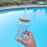 Clear glass cup with bamboo lid and straw featuring blue “She’s Tying the Knot” text and wedding doodles, perfect for brides and iced coffee lovers.