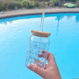 Clear glass cup with bamboo lid and straw featuring blue “She’s Tying the Knot” text and wedding doodles, perfect for brides and iced coffee lovers.