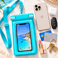 A bright turquoise waterproof phone pouch with a matching neck strap, shown on a light marble surface with a smartphone inside. Surrounding props include a white iPhone, AirPods, car keys, cards, lipstick, and a woven hat, suggesting a beach or travel lifestyle setup.