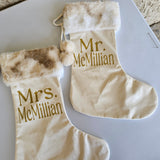 Two personalized Christmas stockings with fur trim on a white surface.