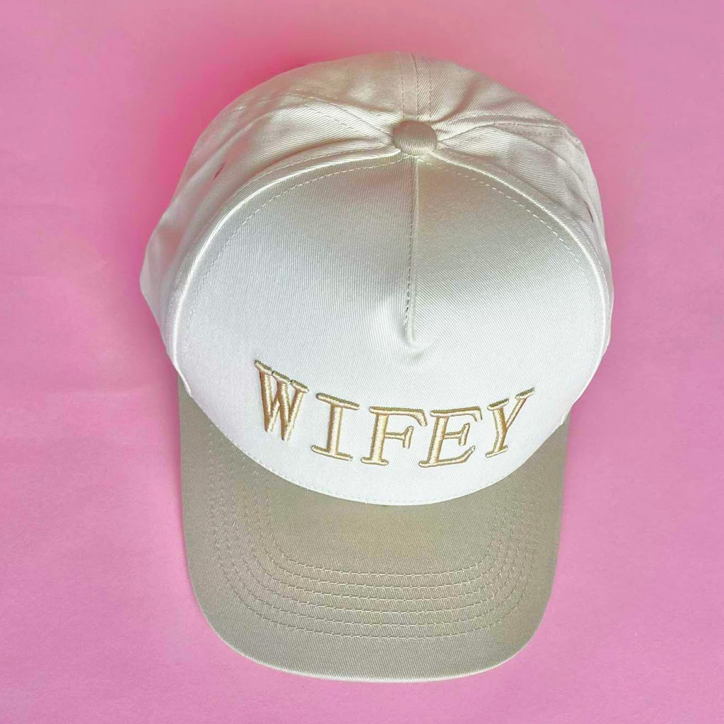 Tan and white trucker hat with embroidered “WIFEY” lettering on the front, a stylish accessory for brides and wives.