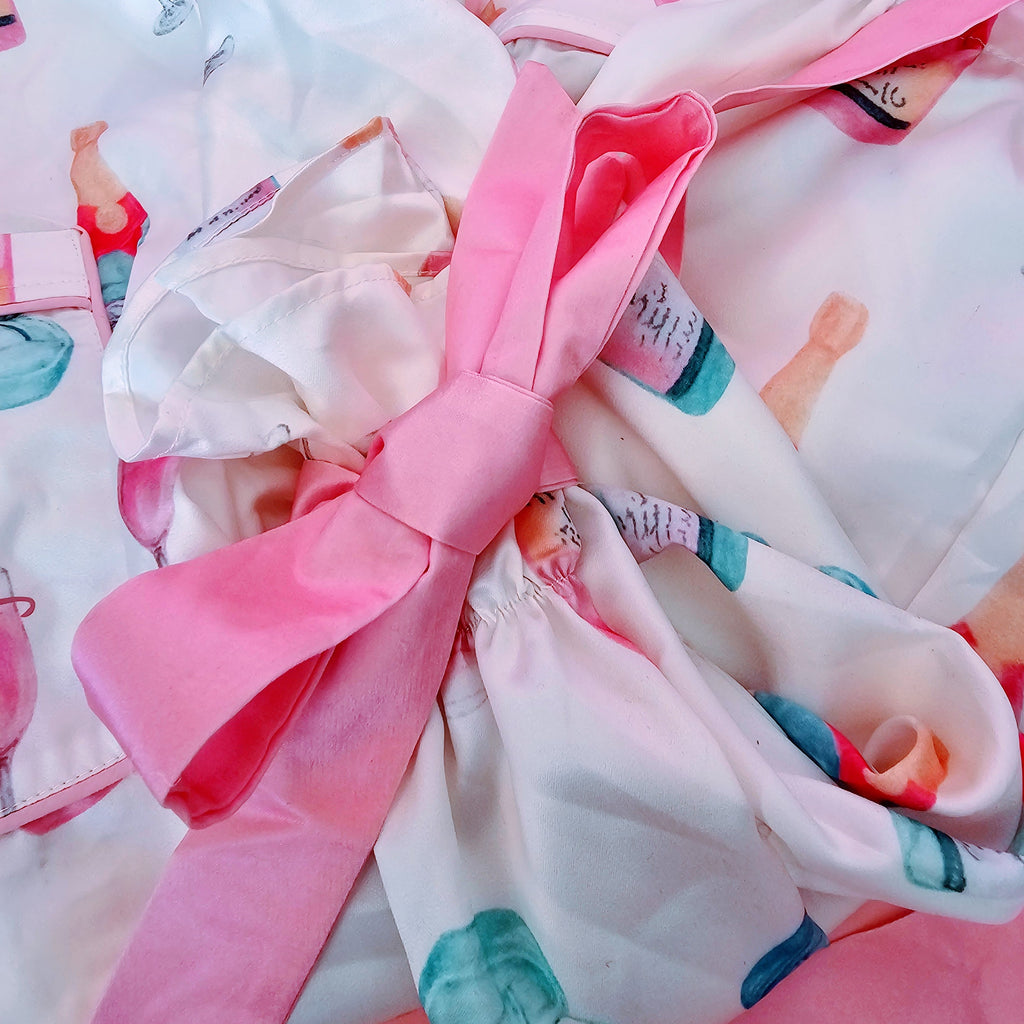 Soft white and pink bridal jammies featuring champagne and ring print for wedding day getting ready moments with bows on the sleeve