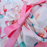 Soft white and pink bridal jammies featuring champagne and ring print for wedding day getting ready moments with bows on the sleeve